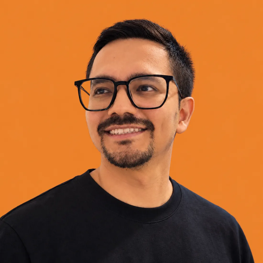 Portrait of Jhoan Zabala smiling, wearing glasses and a black t-shirt
